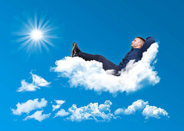 businessman relaxing on a cloud in a blue sky with sun